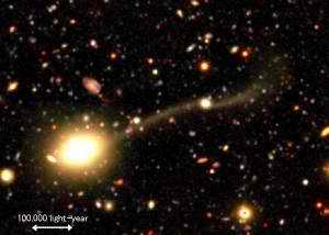 La galaxia elíptica COSMOS J100003+020146 y la galaxia enana COSMOS J095959+020206 unidas por una monumental cola. También puede observarse otra cola a espaldas de la galaxia enana.